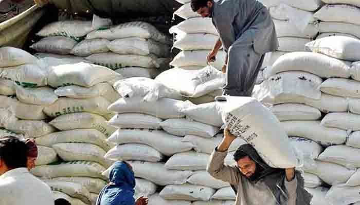 Workers are seen shifting the flour sacks. — APP/File