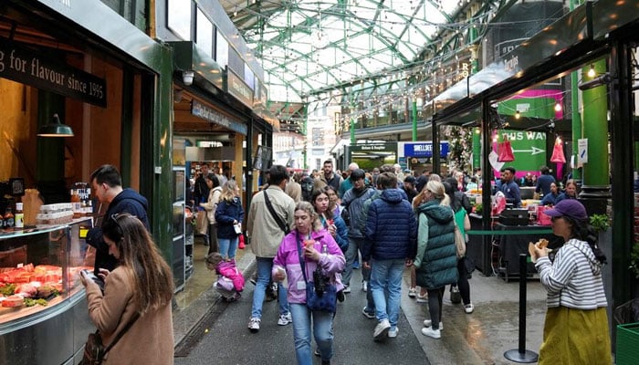 People walk past food stands and market stalls in a Borough Market in London, Britain May 22, 2024. — Retuers