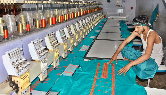 Worker busy in preparing the design on the fabric with help by machine at local textile factory in Hyderabad on May 2, 2024. — APP