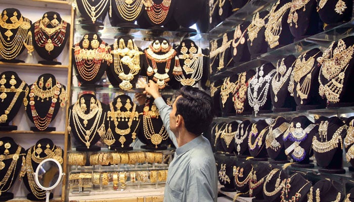 A shopkeeper is displaying gold necklaces at his shop in Moti Bazaar, Rawalpindi on April 18, 2024. — Online/File