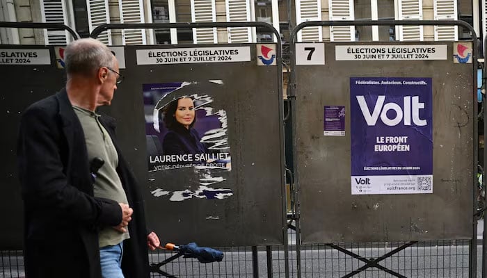 A man walks past election posters outside a polling station, ahead of the French parliamentary elections, in Paris, France, June 22, 2024. — Reuters