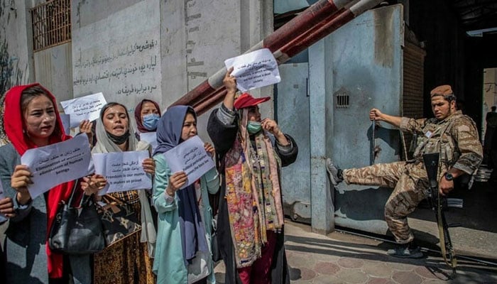 A Taliban member watches as Afghan women hold placards during a demonstration demanding better rights for women in front of the former ministry of women affairs in Kabul. — AFP/File