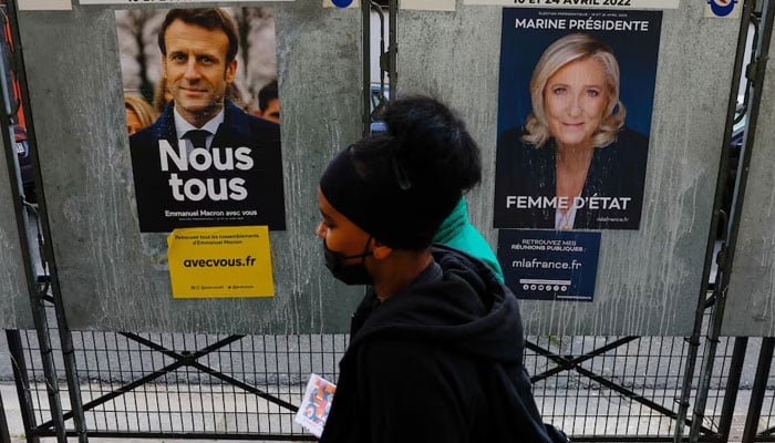 People walk past official campaign posters of French presidential election candidates Marine le Pen, leader of French far-right National Rally (Rassemblement National) party, and French President Emmanuel Macron, candidate for his re-election, displayed on bulletin boards in Paris, France, April 4, 2022. — Reuters