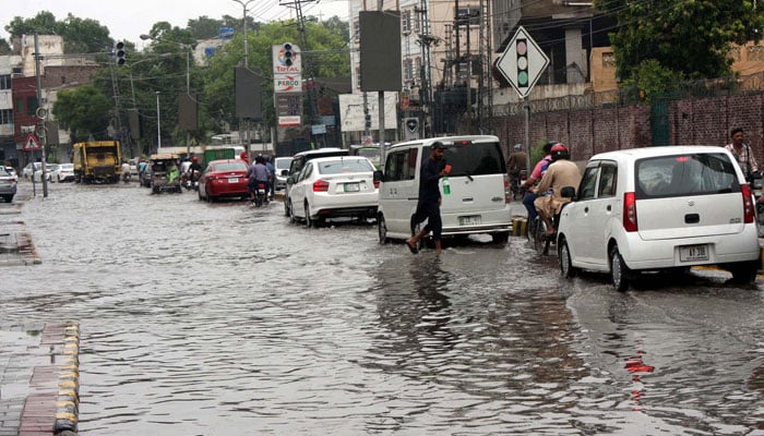 Commuters are facing difficulties in transportation due to stagnant rainwater due to poor sewerage system caused by heavy downpour of monsoon season, at Queens road in Lahore on Monday, July 1, 2024. — APP
