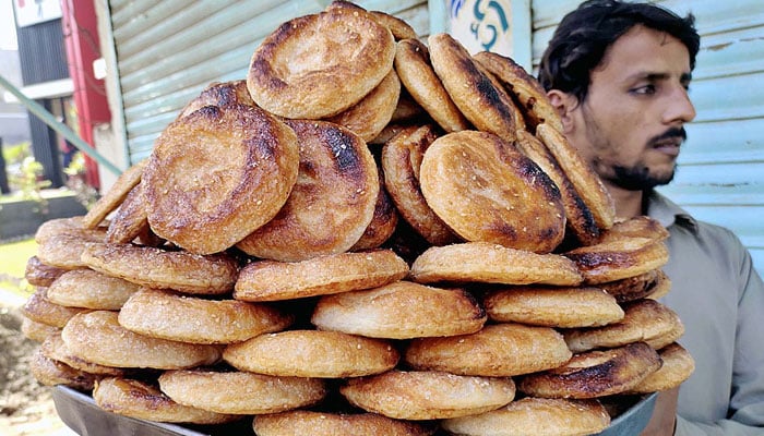 A street vendor carrying a try of bakery item Puff pastry on his shoulder for selling at Royal Road in Larkana on Feb 6, 2023.  — APP