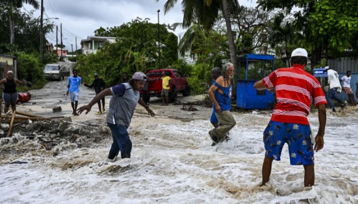 People walk through flooding from seawater after the passage of Hurricane Beryl in the parish of Saint James, Barbados. — AFP/file