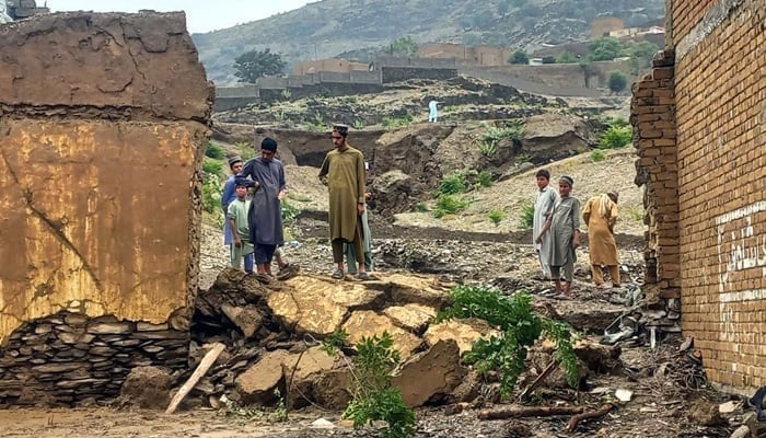 A representational image showing people standing near a collapsed wall after floods due to heavy monsoon rain in Landikotal. — PPI/File