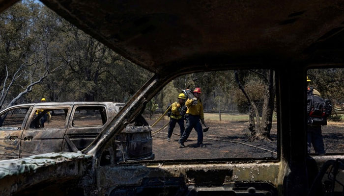 Firefighters walk near burned vehicles after the Thompson fire affected a neighbourhood near Oroville, California. — Reuters/File