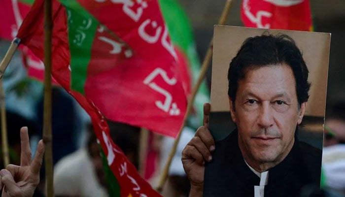 An activist of the opposition party Pakistan Tehreek-e-Insaf (PTI) holds a portrait of Pakistan´s former Prime Minister Imran Khan during a rally on October 28, 2022. — AFP