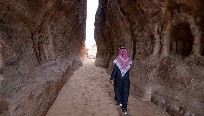 A picture taken on February 3, 2023 shows a man walking around Ancient Nabataean carved tombs at the archaeological site of al-Hijr (Hegra), near the northwestern Saudi city of al-Ula. — AFP