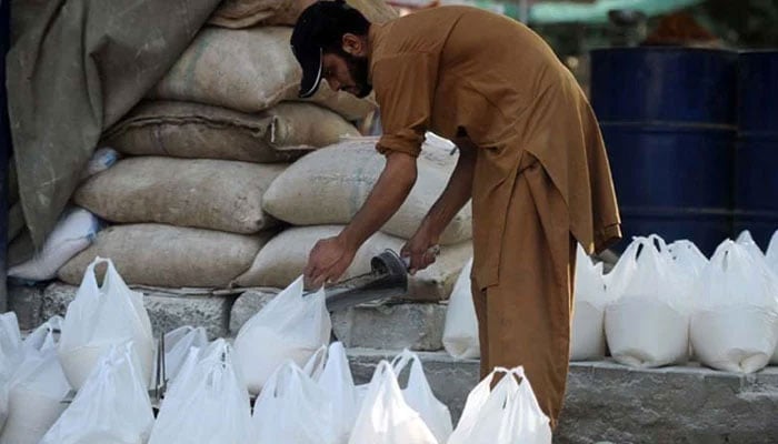 A Pakistani worker prepares bags of wheat flour. —AFP/File