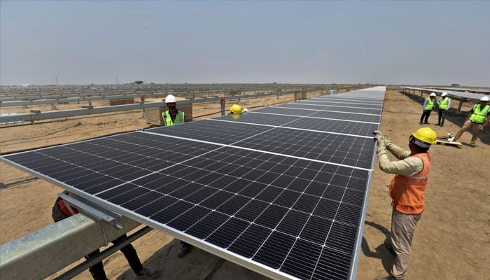 Workers install solar panels at the Khavda Renewable Energy Park of Adani Green Energy Ltd (AGEL) in Khavda, India, April 12, 2024. — Reuters