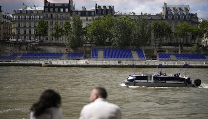 People sit along the Seine river with stands installed on its banks, Thursday, July 4, 2024 in Paris. — AFP