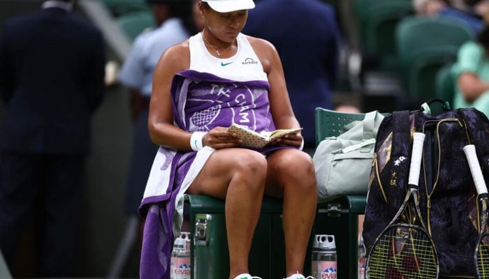 Naomi Osaka reads during a break in play against Emma Navarro at Wimbledon — AFP/file