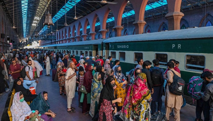People wait to board a train at a railway station in Lahore on June 15, 2024. — AFP