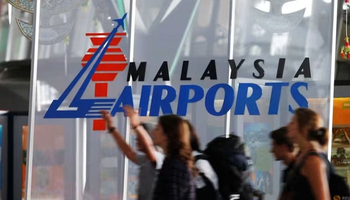 Travellers push their trolley past a logo of Malaysia Airports at the departure hall of Kuala Lumpur International Airport in Sepang, outside Kuala Lumpur on Aug 26, 2013. — Reuters