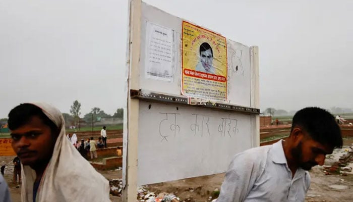 People stand near a poster of preacher Surajpal, also known as Bhole Baba stuck on a board. — Reuters/file