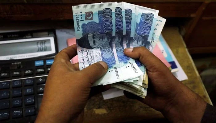 A trader counts Pakistani rupee notes at a currency exchange booth in Peshawar, Pakistan December 3, 2018. — Reuters