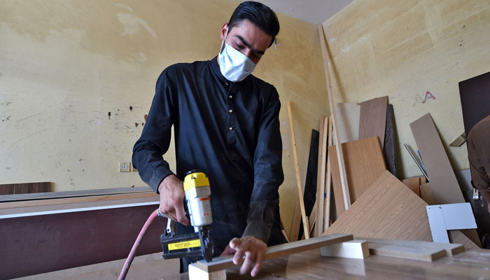 Pakistani carpenter wears a protective mask as he works at a carpentry workshop. — AFP/file