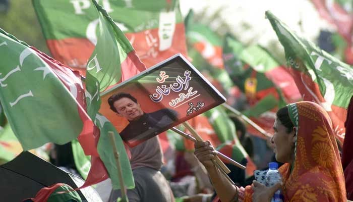 Supporters of PTI hold party flags during a public gathering (jalsa) at Parade Ground, in Islamabad. — Online/File