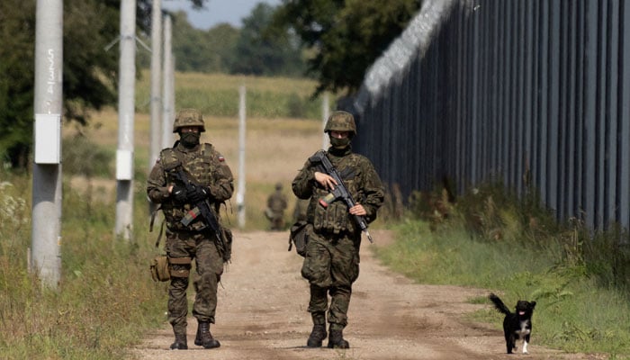 Polish soldiers and a local dog walk along the border fence on the Polish-Belarusian border in Usnarz Gorny, Poland, August 30, 2023. — Reuters