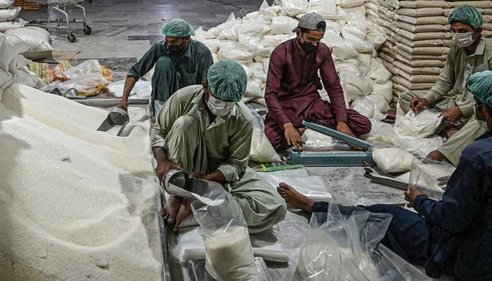 Workers prepare sugar bags at a warehouse in Islamabad. — AFP/File