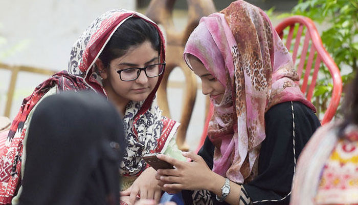 A representational image showing students using their mobile phones at a university in Islamabad. — AFP/file