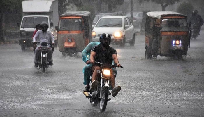 Vehicles pass through rainwater accumulated on the road in Kalma Chowk during heavy rain in Lahore on June 29, 2024. — APP