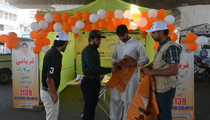 The Rawalpindi Waste Management Company (RWMC) team distributes biodegradable bags and pamphlets to create awareness among the people at a camp on June 9, 2024. — Facebook/Rawalpindi Waste Management Company