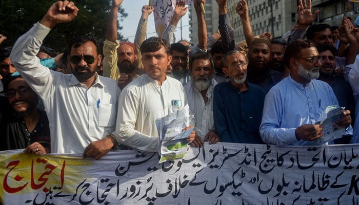 Traders shout slogans as they hold a banner during a protest against the surge in electricity prices along a street in Karachi on August 30, 2023. — AFP