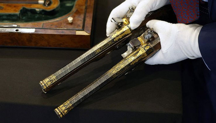 A staff member shows two pistols, which belonged to Emperor Napoleon I, during the preview before their auction. — AFP/file