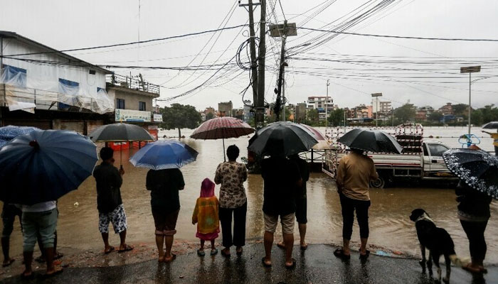 People look towards a flooded area along the bank of overflowing Bagmati River following heavy rains in Kathmandu, Nepal, July 6, 2024. — Reuters