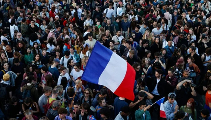 People hold French flags as they gather at the Place de la Republique after partial results in the second round of the early French parliamentary elections, in Paris, France. — Reuters/File