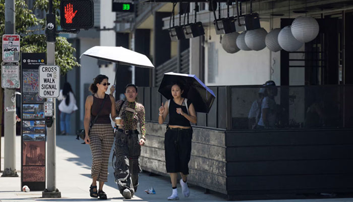 People hold an umbrella to protect themselves from the sun in Little Tokyo during hot weather in Los Angeles, California, US July 5, 2024. — Reuters