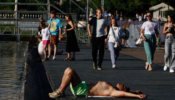 A man lies near a fountain in a park during hot weather in Moscow, Russia on July 2, 2024. — Reuters