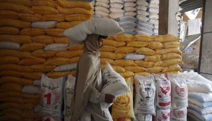 A person carrying a bag of flour on his and one in his hands. — Reuters/File