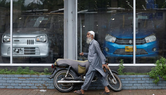 A representational image showing a man walking past a car showroom in Karachi on July 27, 2022.— Reuters