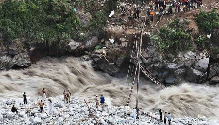 Representational image shows men stand on the banks of a water stream caused by flooding in Chitral, Khyber Pakhtunkhwa. — AFP/File