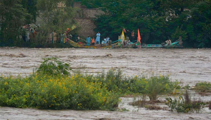 People stand alongside the Khiyali River in district Charsadda as flash floods wreak havoc. — APP/File