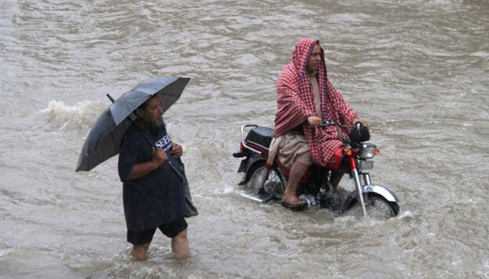 A man holds an umbrella as he walks through floodwaters during heavy rain in Lahore, Pakistan, July 3, 2018. — Reuters