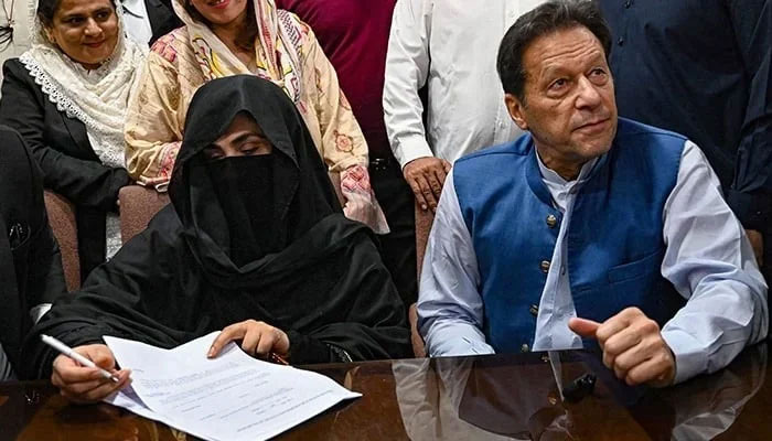 PTI founder Imran Khan (right) along with his wife Bushra Bibi who is signing surety bonds for bail in various cases, at a registrar office in the High court, in Lahore on July 17, 2023. — AFP