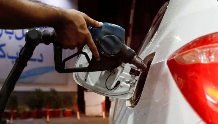 A worker holds a fuel nozzle to fill up a cars fuel tank at a petrol station in Karachi. — Reuters/file