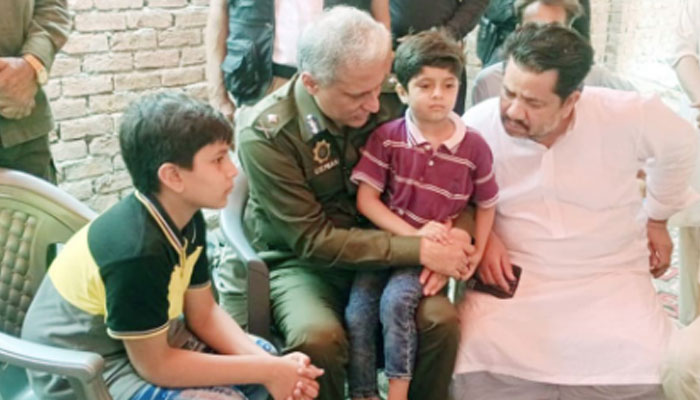 IGP Punjab sits the child in his lap while visiting the residence of ASI M Nawaz of PHP who embraced martyrdom by firing of dacoits in the Sheikhupura area on July 17, 2024. — Facebook/Punjab Police Pakistan