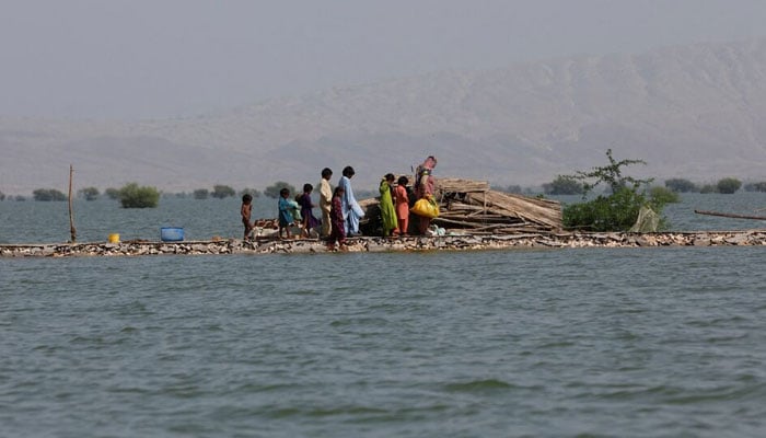 A woman and children walk as they take refuge along a damaged road amid flood, following rains and floods during the monsoon season in Bajara village, at the banks of Manchar lake, in Sehwan, Pakistan September 6, 2022. — Reuters