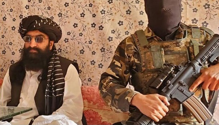 Tehreek-e-Taliban Pakistan (TTP) Chief Noor Wali Mehsud (L) speaks to journalists while his sucurity guard stands alert. — X/ @War_Analysts/File