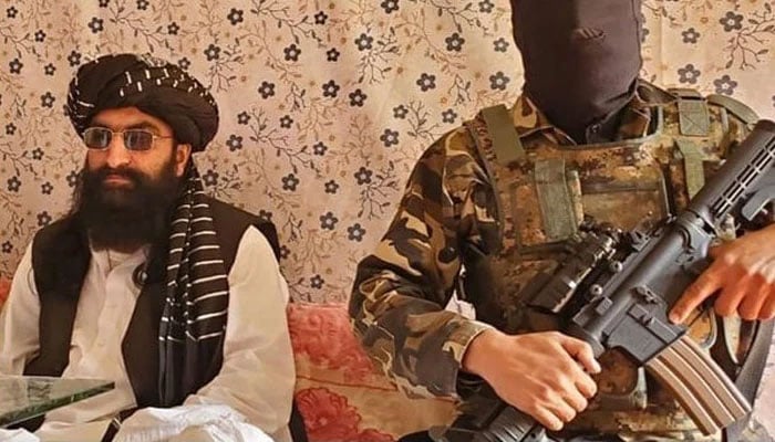 Tehreek-e-Taliban Pakistan (TTP) Chief Noor Wali Mehsud (L) speaks to journalists while his sucurity guard stands alert. — X/ @War_Analysts/File