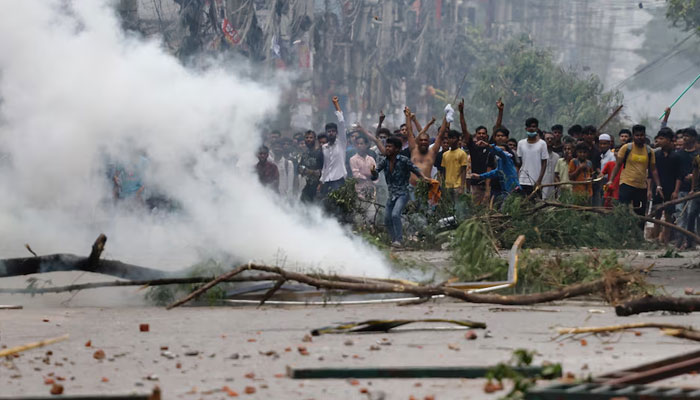 People gesture near smoke as protesters clash with Border Guard Bangladesh (BGB) and the police outside the state-owned Bangladesh Television as violence erupts across the country after anti-quota protests by students, in Dhaka, Bangladesh, July 19, 2024. — Reuters