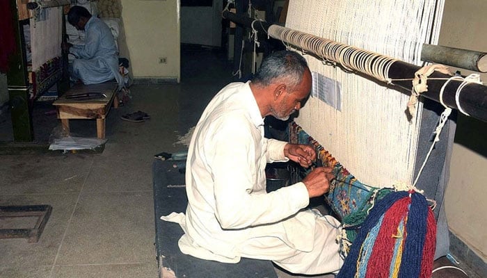 A man busy in preparation of handmade carpets with the help of traditional machine to earn his livelihood for support his family, at workplace in Lahore on Sunday, November 12, 2023. — PPI