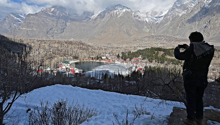 A tourist takes pictures of the Lower Kachura Lake at the Shangrila Resort, about 6 Km from Skardu on January 24, 2021. —AFP