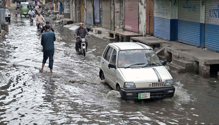 Vehicles pass through rainwater accumulated on the road at Imambara Mohallahon on July 23, 2024. — APP